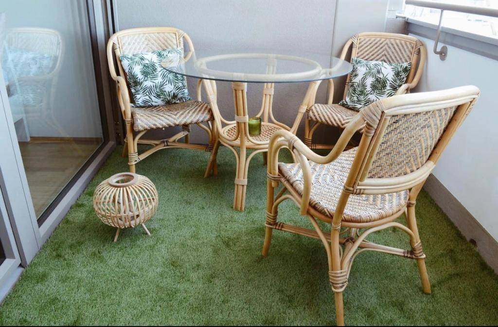 Balkon mit Rattanmöbeln und Kunstrasen, ideal für entspannte Stunden im Freien.