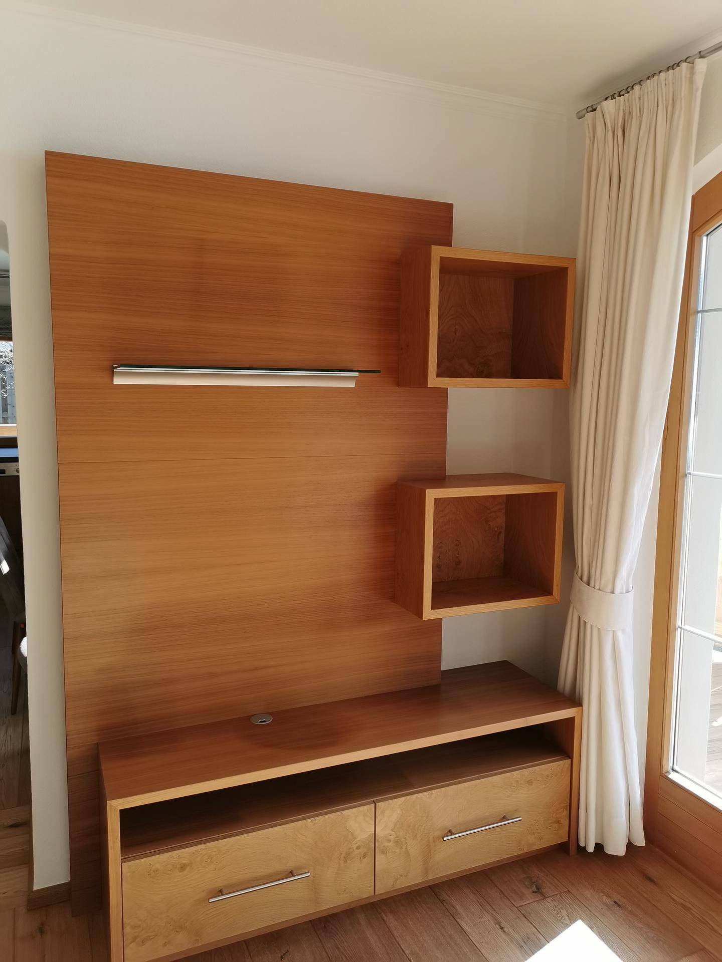 Moderne Holz-Wandregal mit integrierten Schubladen neben einem Fenster.