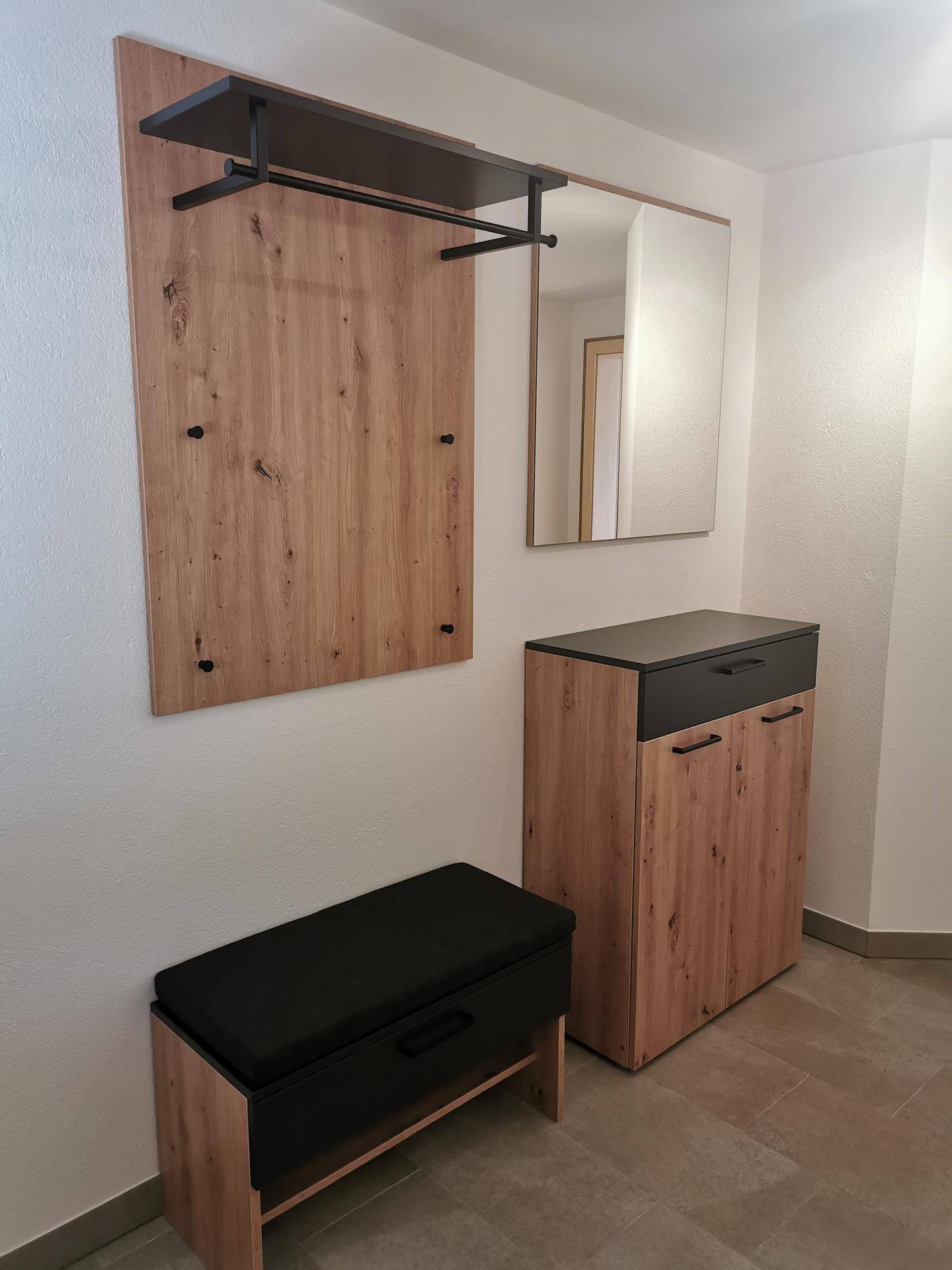 Moderner Flur mit Garderobe, Spiegel und Schuhschrank in Holzoptik.