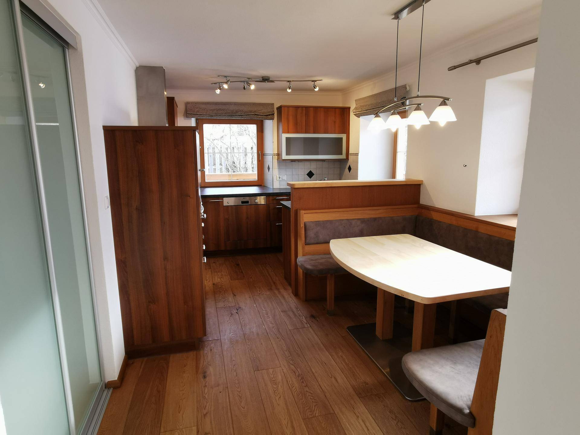 Helle Küche mit Holzelementen, integriertem Essbereich und Holzdielenboden.