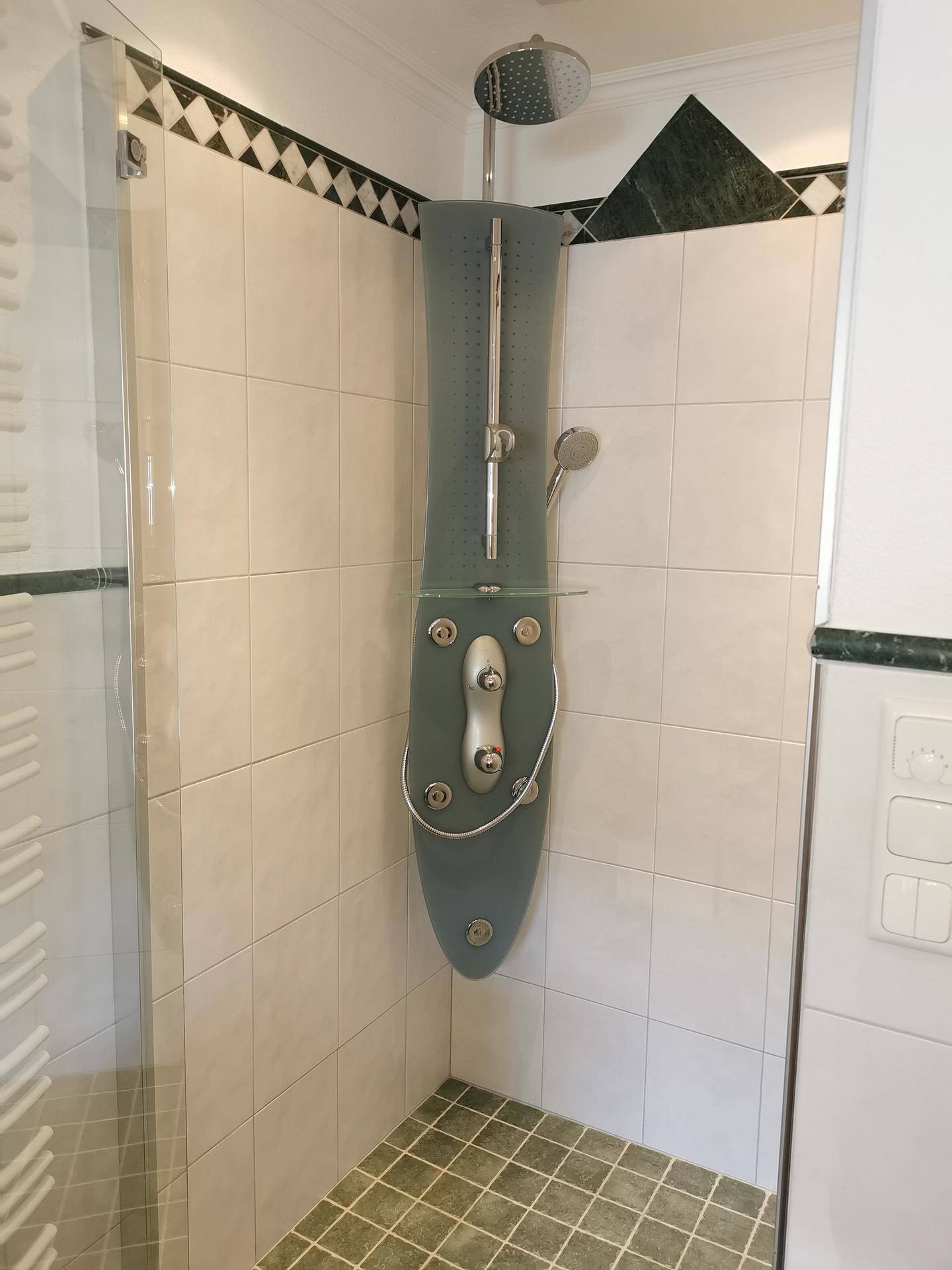 Duschkabine mit modernem Duschpaneel und weißen Wandfliesen im Badezimmer.