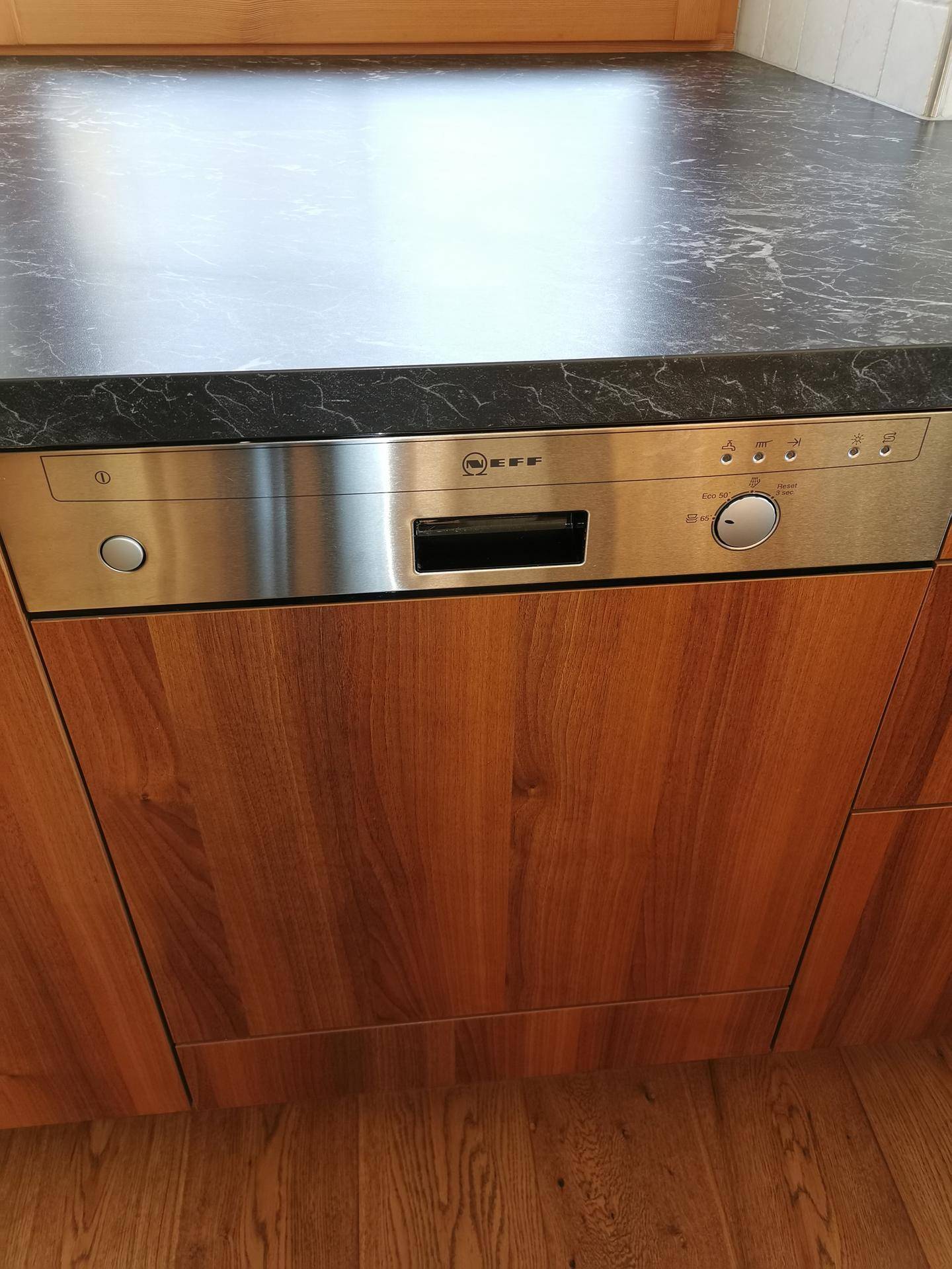 Integrierter Geschirrspüler aus Edelstahl in der Holzfront der Einbauküche.