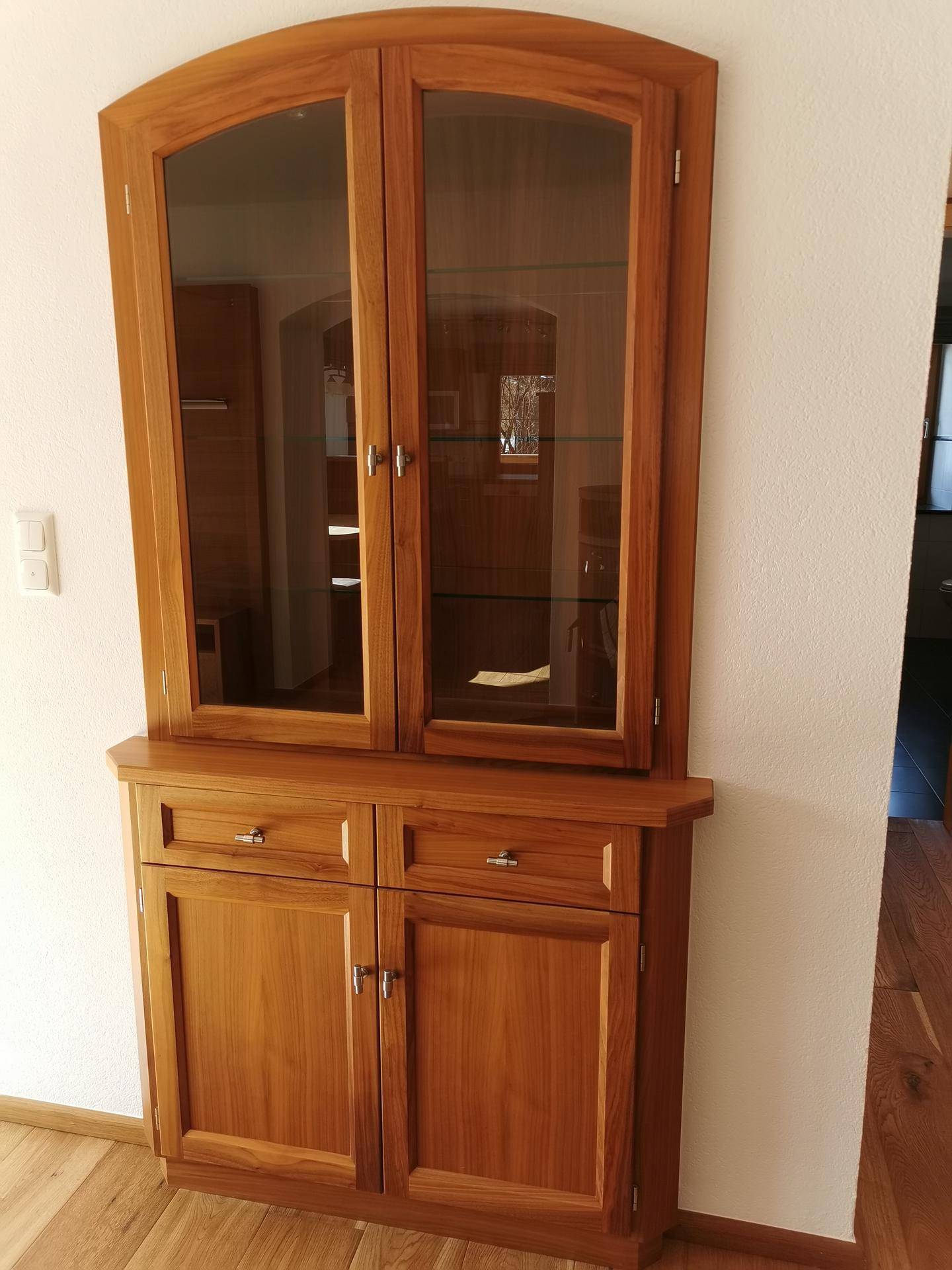 Traditionelle Holzvitrine mit Glastüren und Schubladen, passend zum rustikalen Stil.