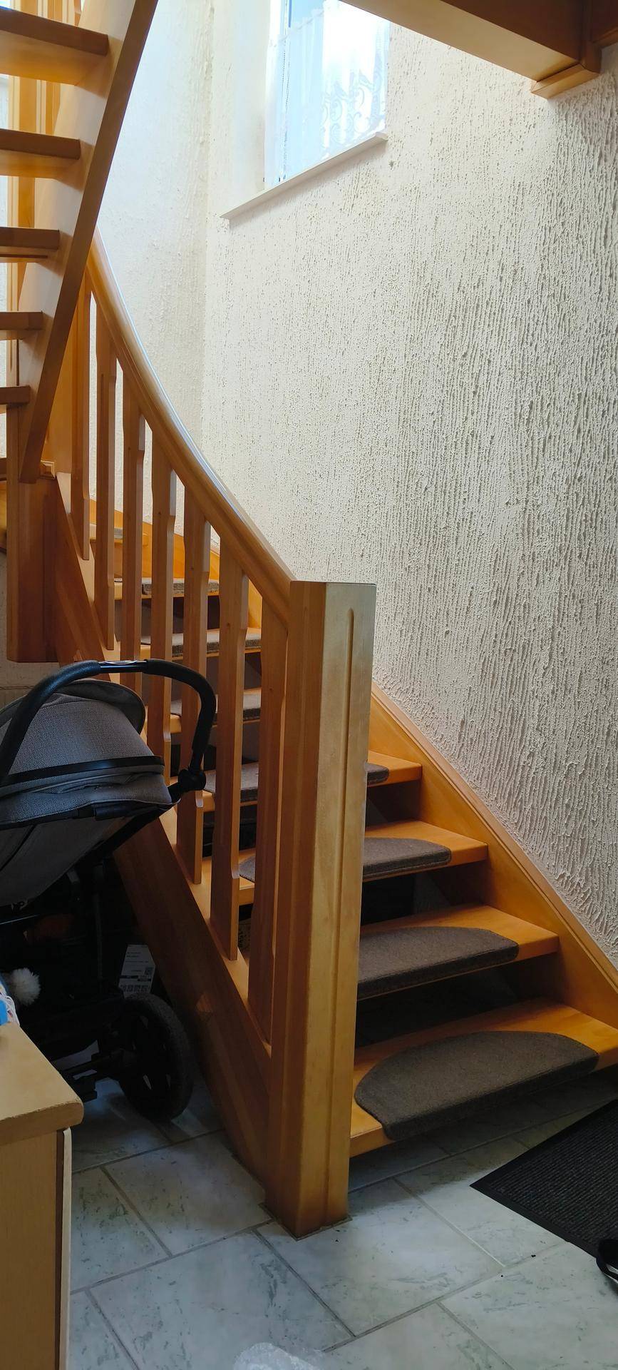 Helle Holztreppe mit Geländer, die die Stockwerke des Hauses miteinander verbindet.