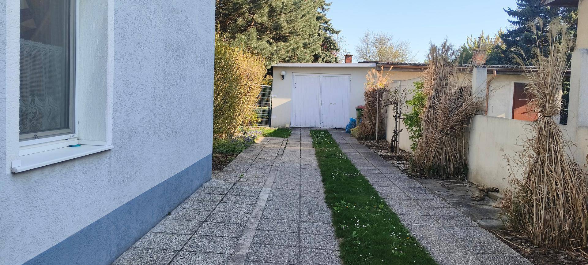 Gepflasterte Einfahrt führt zu einer freistehenden Garage im hinteren Bereich des Grundstücks.