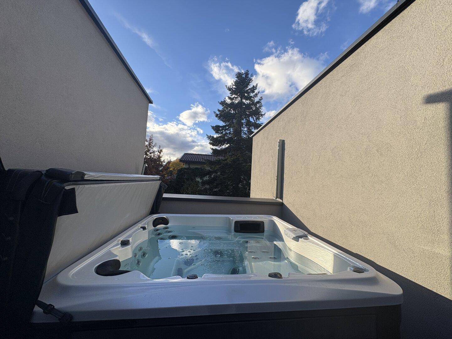 Entspannungsbereich im Freien mit einem sprudelnden Whirlpool unter blauem Himmel.