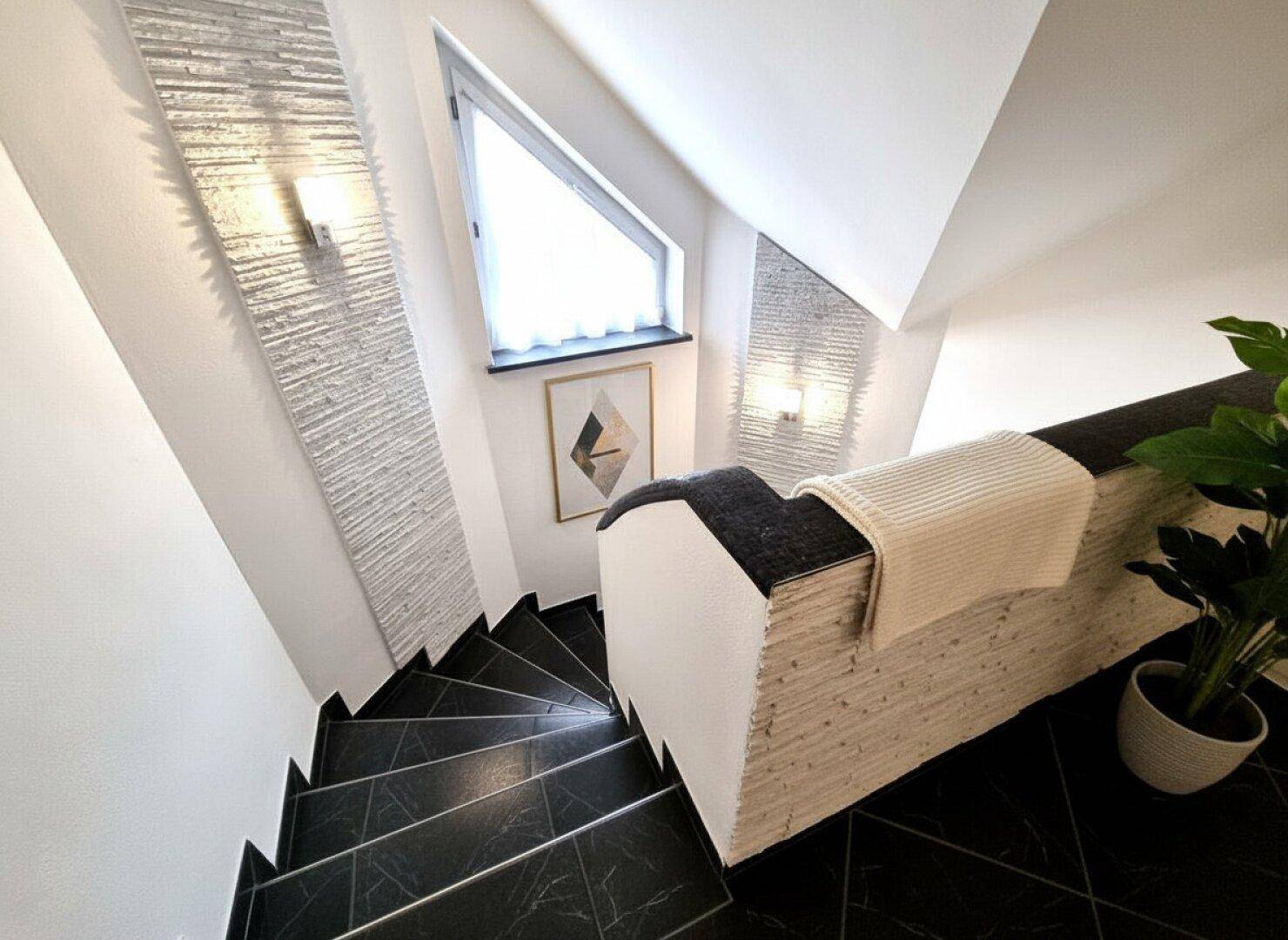 Elegante Treppe mit dunklen Fliesen und modernem Geländer, die in die obere Etage führt.