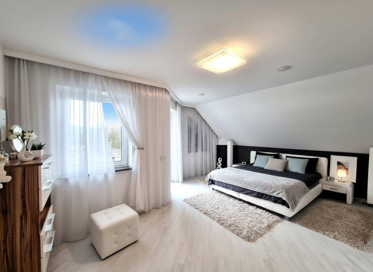 Helles Schlafzimmer mit hellem Boden, großem Bett und schrägen Decken, bietet eine gemütliche Atmosphäre.