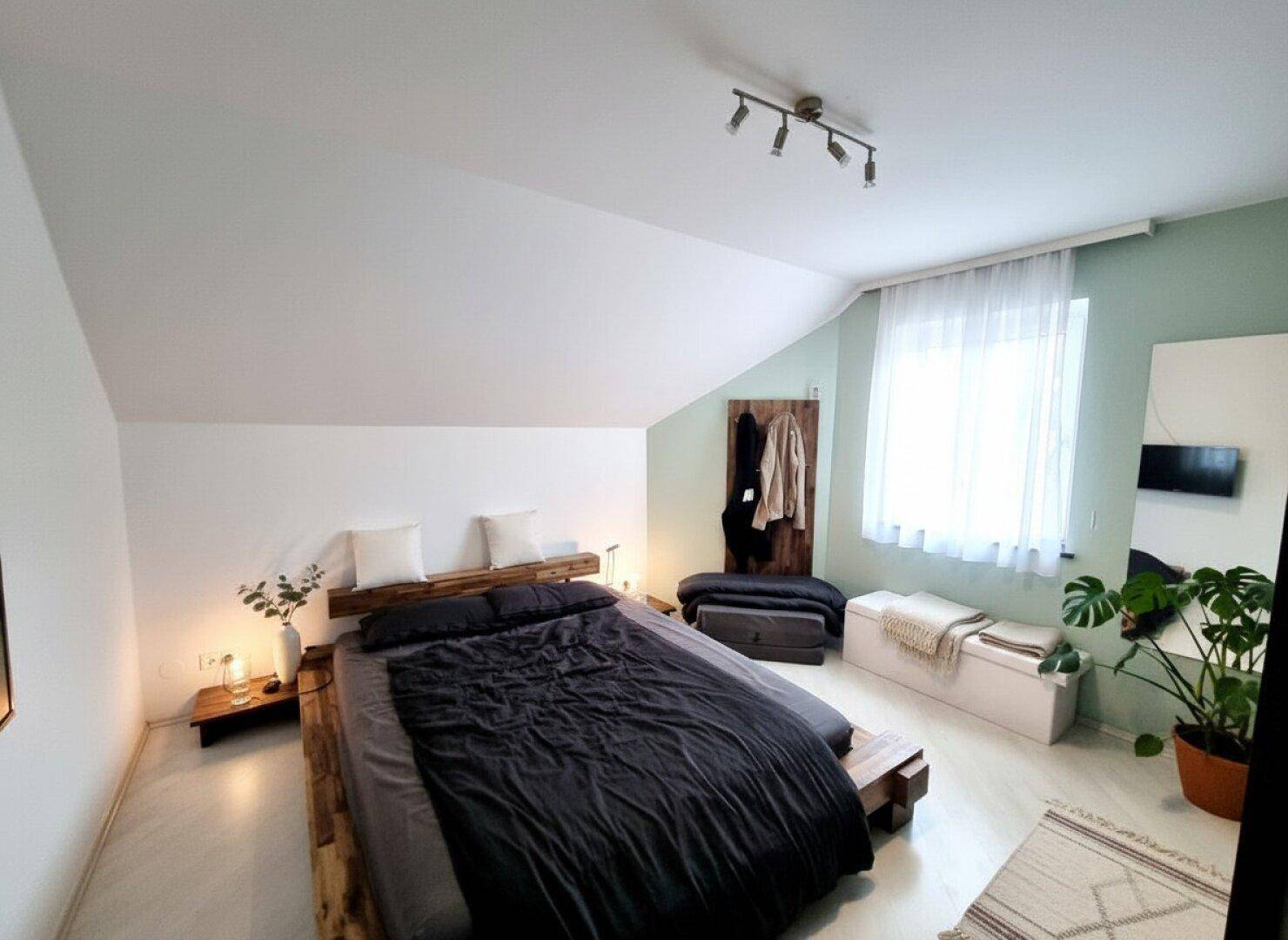 Gemütliches Schlafzimmer mit hellem Boden, modernem Bett und farbigen Wänden, ideal zum Entspannen.
