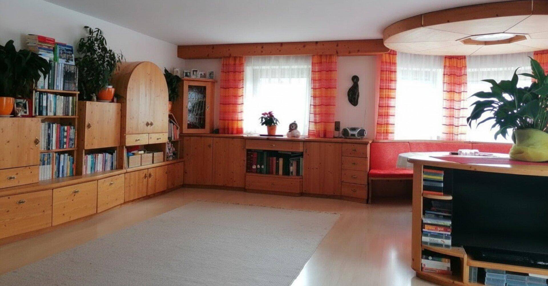 Helles Wohnzimmer mit maßgefertigten Holzregalen, runder Deckenverkleidung und großen Fenstern.