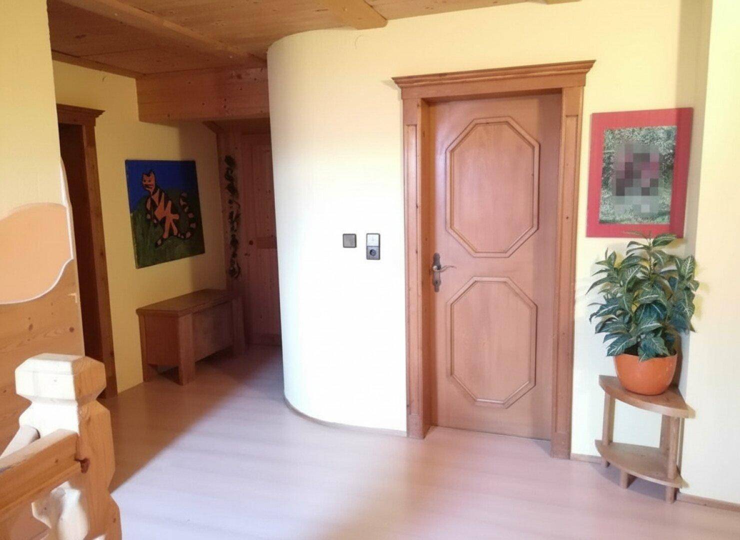 Heller Flur mit Holztüren, hellen Wänden und dekorativer Zimmerpflanze.