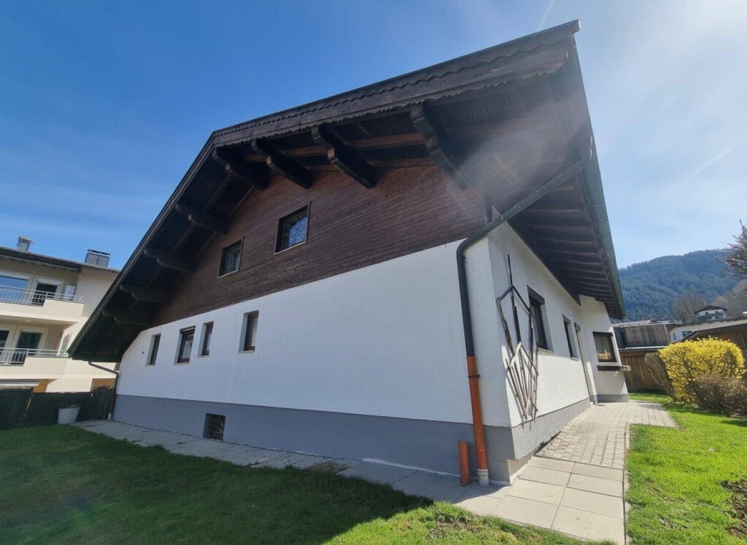 Seitenansicht des Hauses mit traditionellem Dachüberstand und kleinem Gartenbereich.