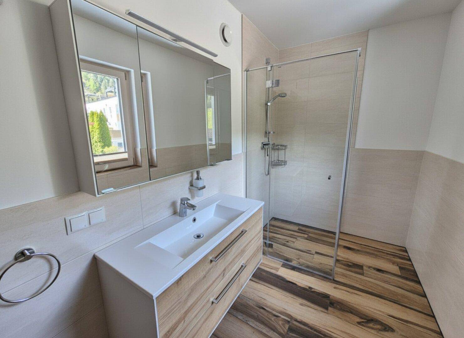Modernes Badezimmer mit Waschtisch, Spiegelschrank und ebenerdiger Dusche.