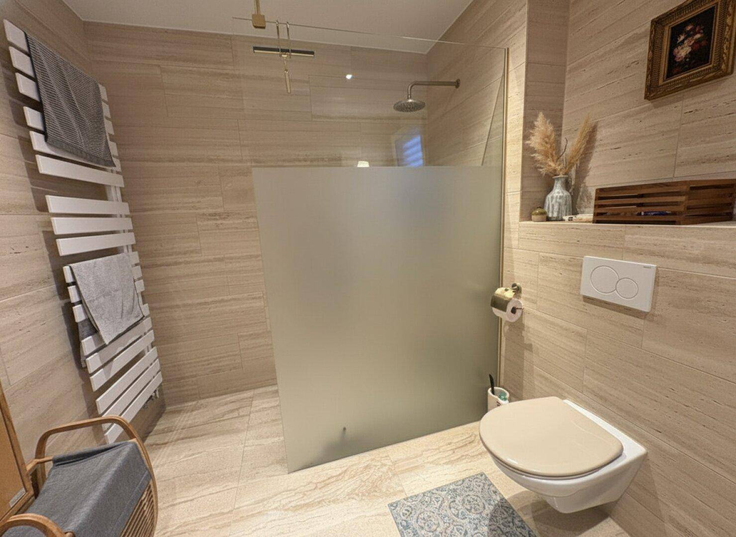 Modernes Badezimmer mit begehbarer Dusche, Wand-WC und beheiztem Handtuchhalter.