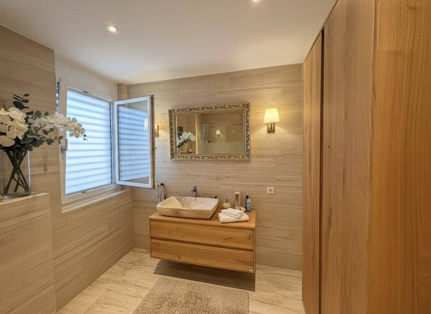 Elegantes Badezimmer mit Holzwaschtisch, Aufsatzwaschbecken und großen Fliesen.