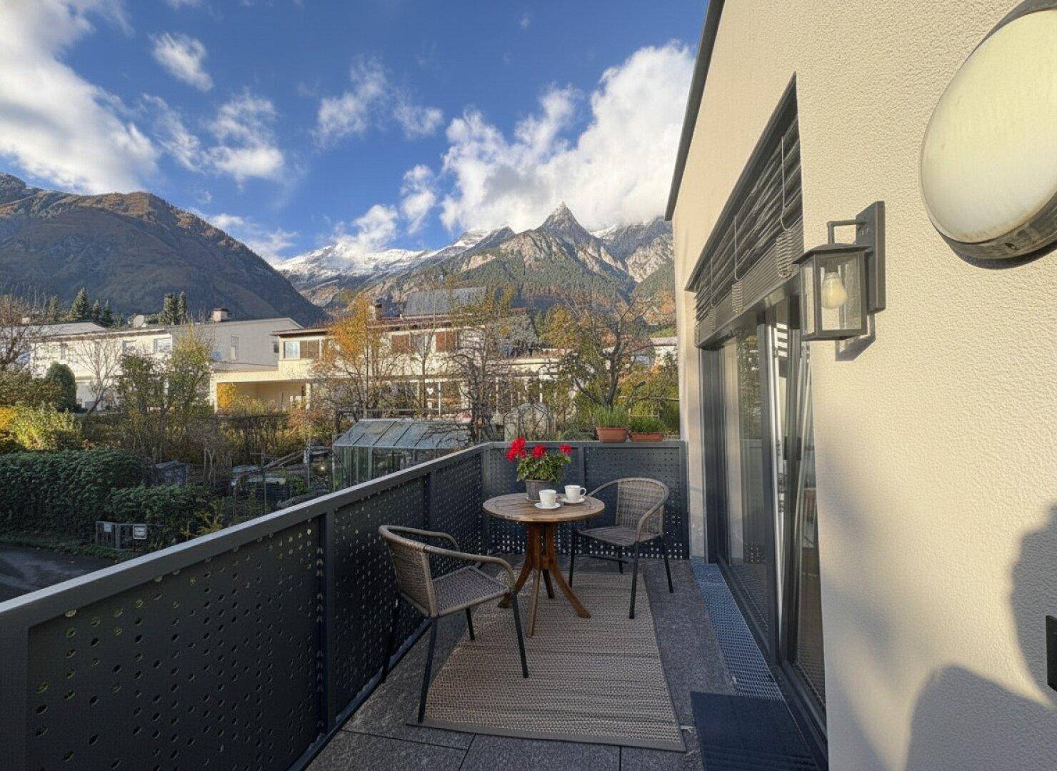 Balkon mit Sitzgelegenheiten und atemberaubendem Blick auf die umliegenden Berge.