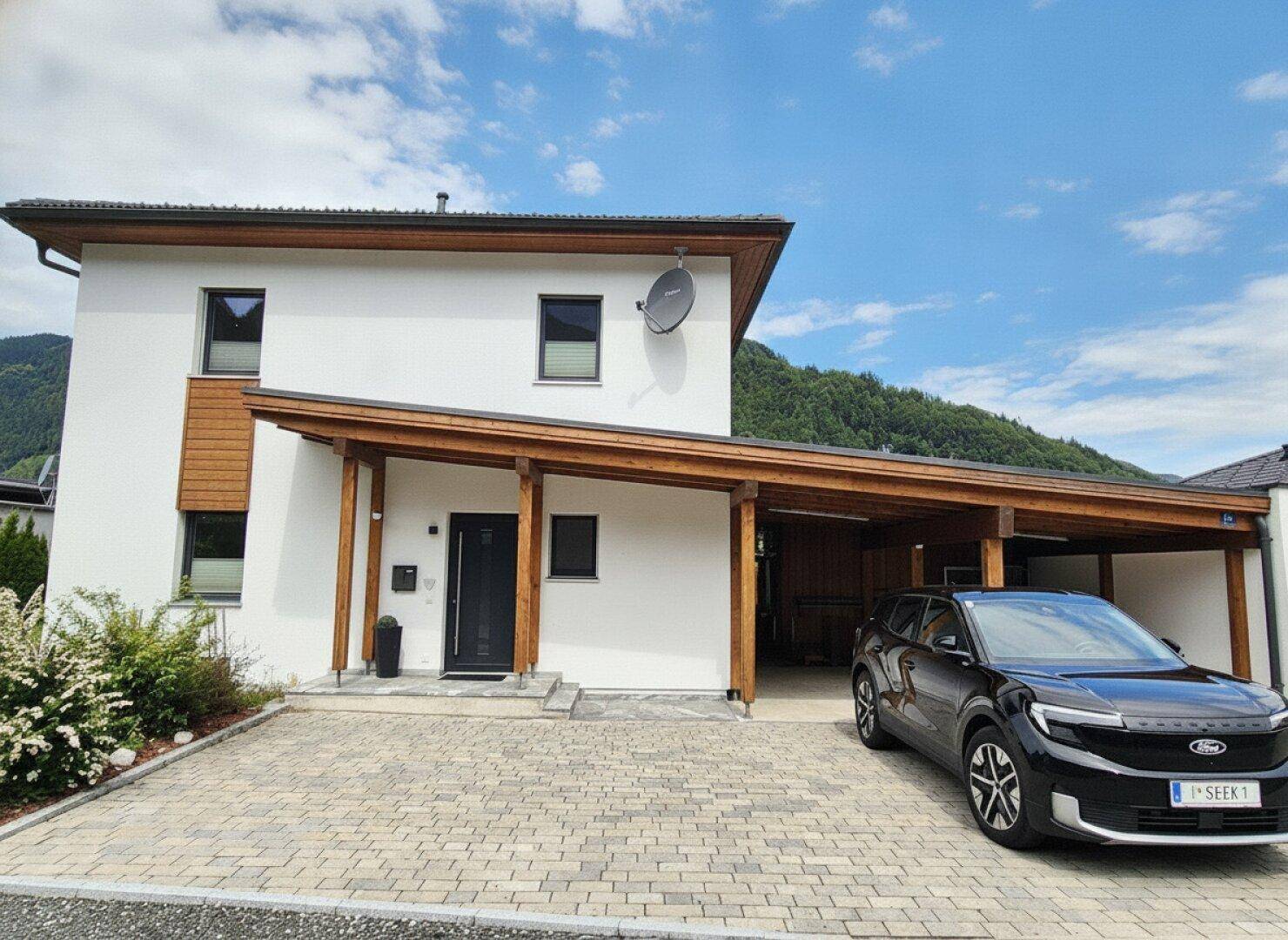 Vorderansicht des modernen Hauses mit Carport und gepflasterter Auffahrt.