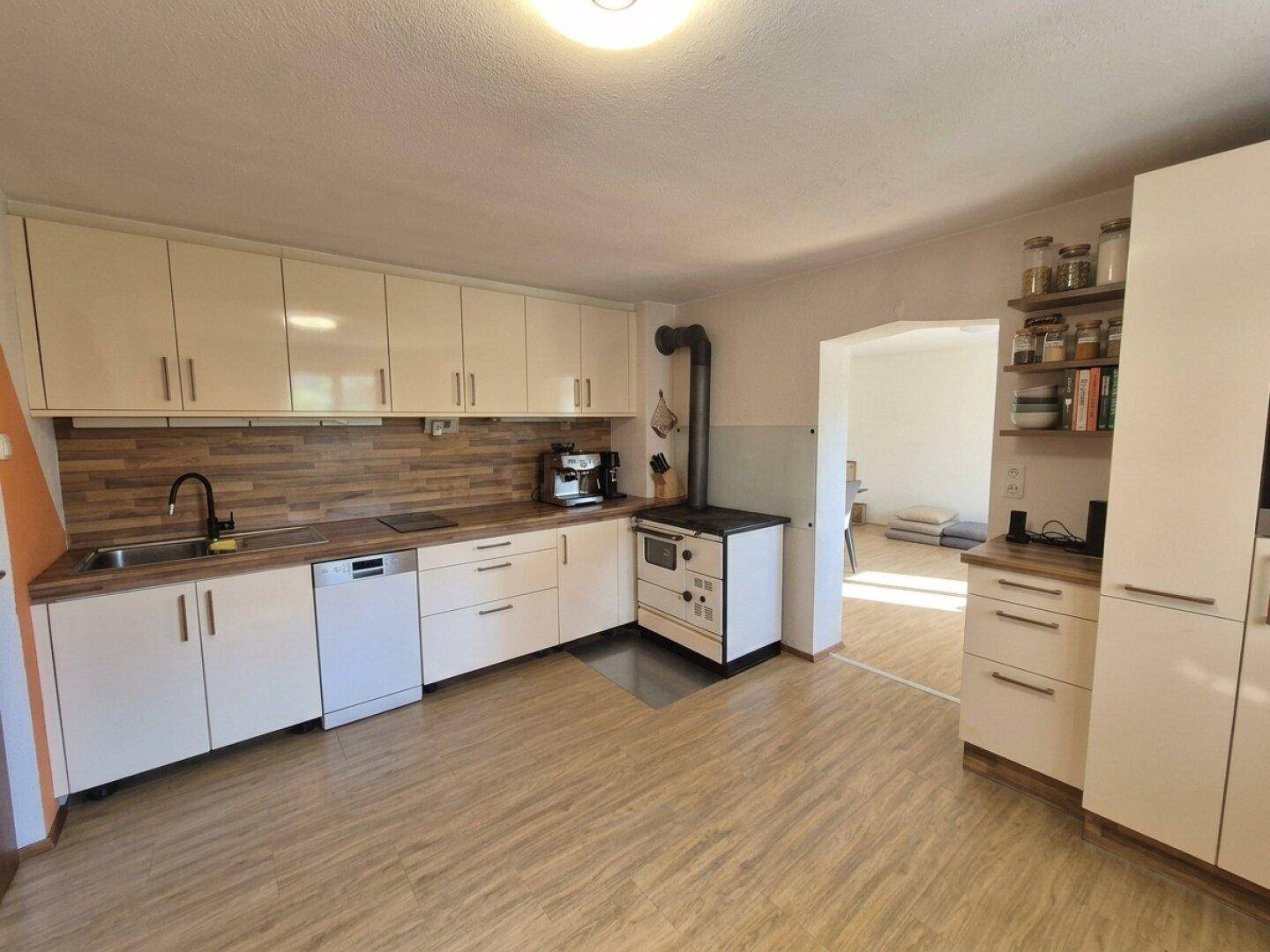 Moderne Küche mit hellen Schränken, Holzarbeitsplatten und traditionellem Holzofen.