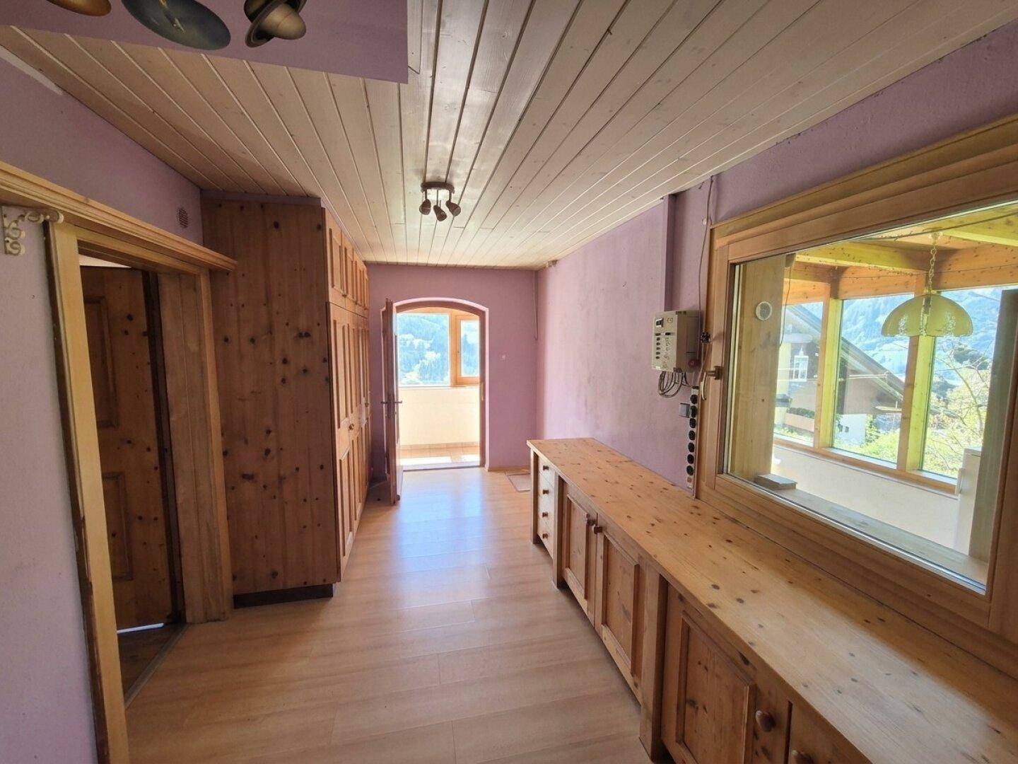 Flur mit Holzvertäfelung, Einbauschränken und Zugang zu einem kleinen Balkon.