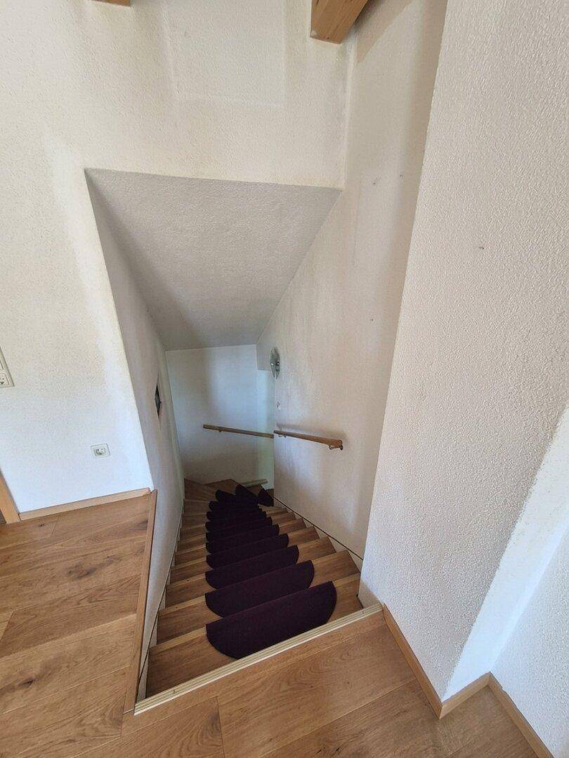 Holztreppe mit Teppichläufern, die in die untere Etage führt.