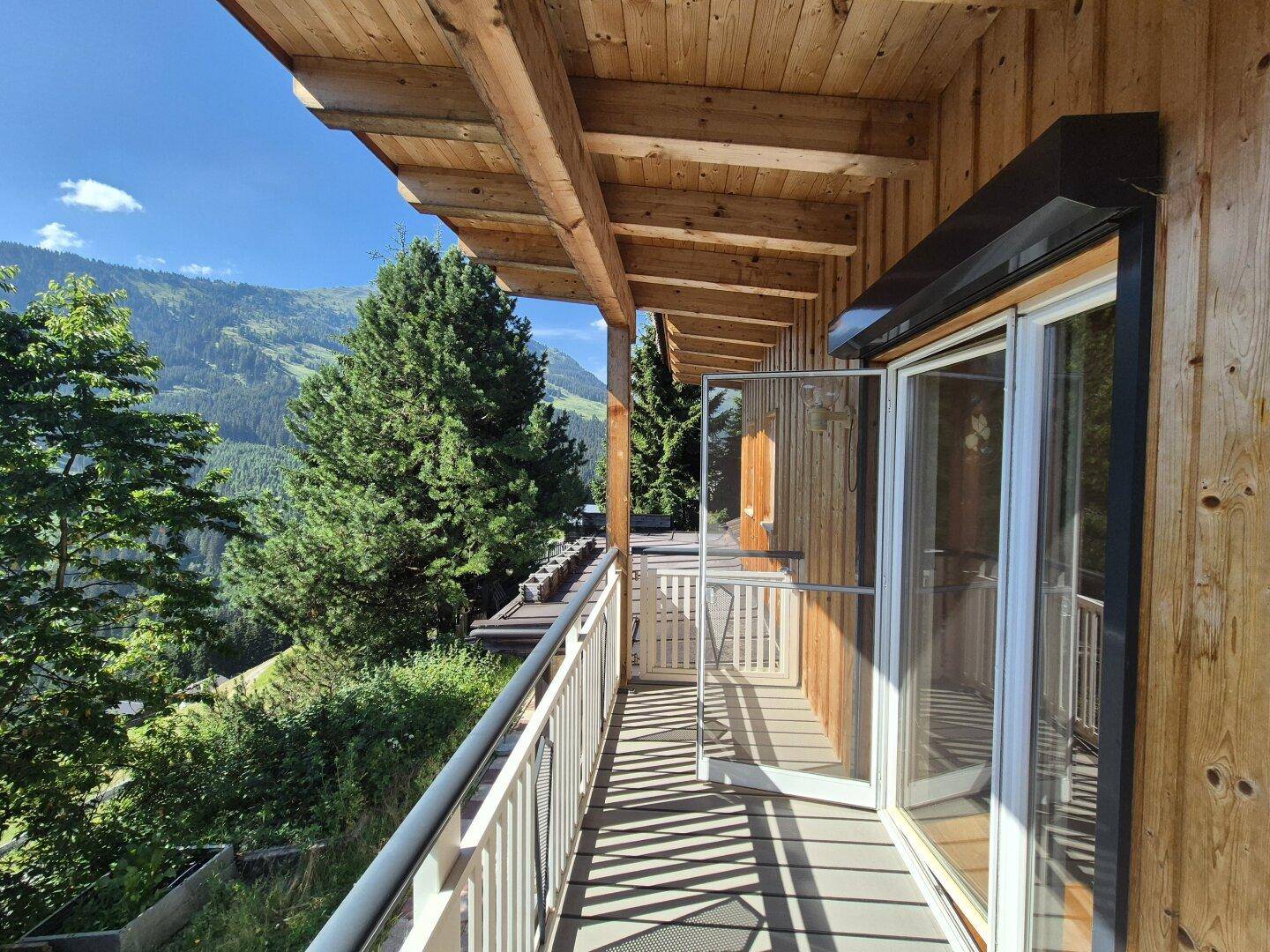 Geräumiger Balkon mit Holzbalkendecke und atemberaubendem Blick auf die Berge und das Tal.