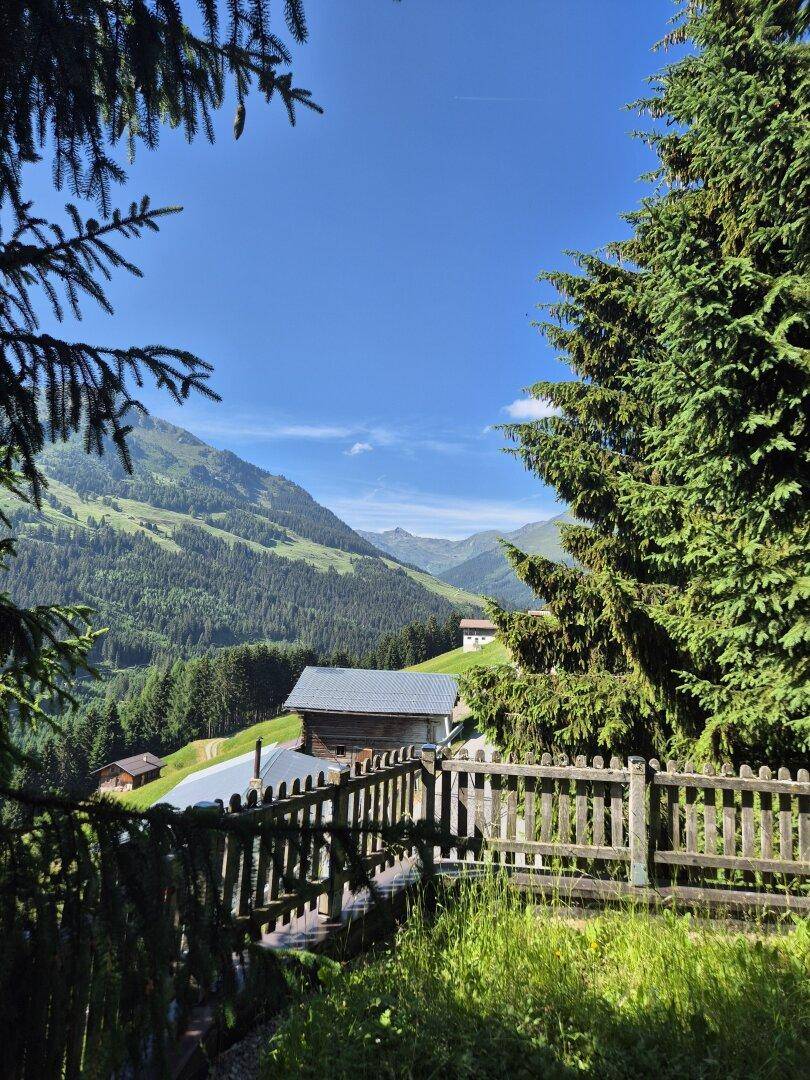 Malerischer Blick auf die grüne Berglandschaft mit traditionellen Häusern im Tal.