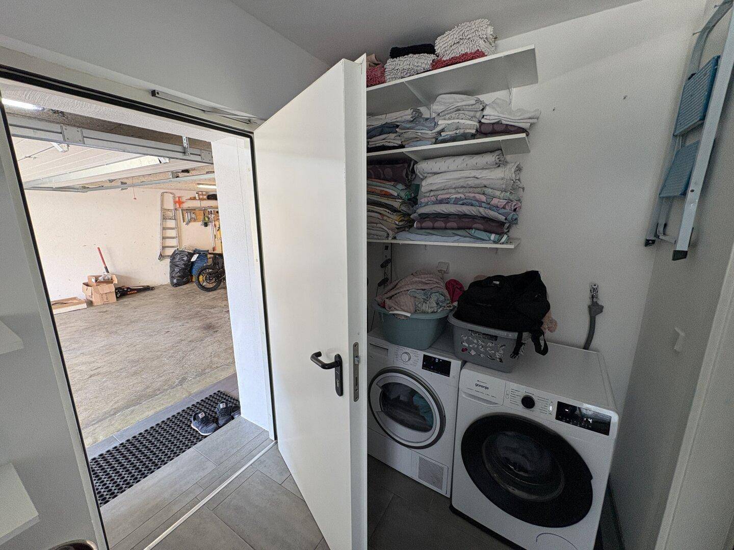 Praktischer Hauswirtschaftsraum mit Waschmaschine, Trockner und direktem Zugang zur Garage.