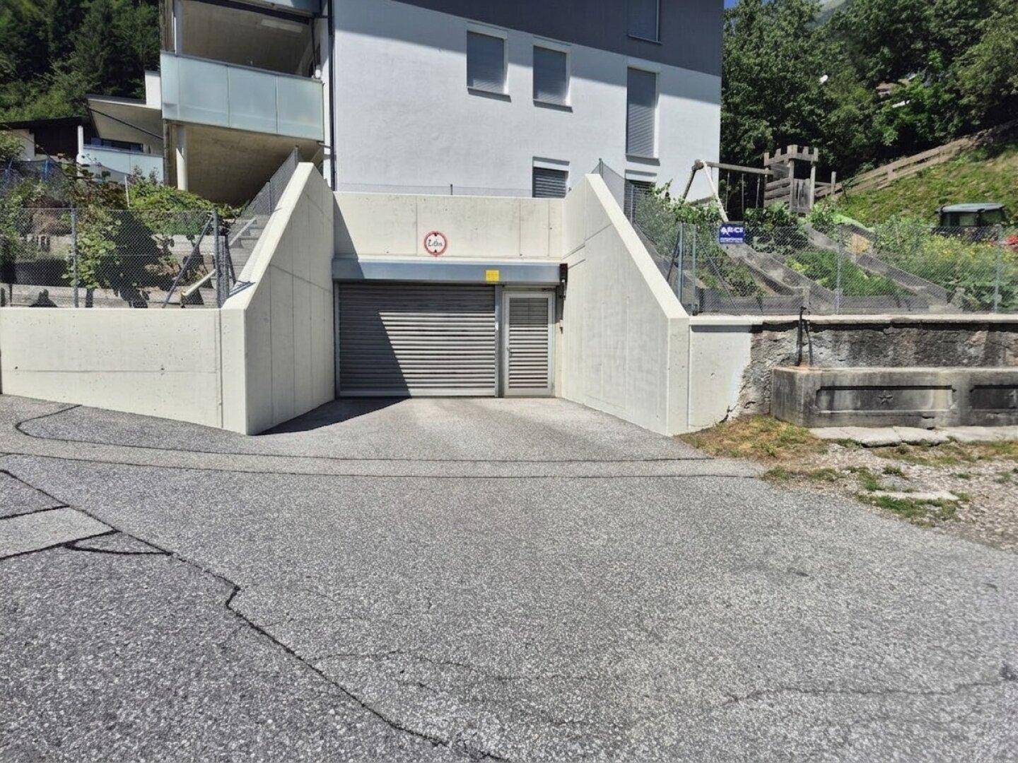 Eingang zur Tiefgarage mit Rolltor und Zufahrt von der Straße.