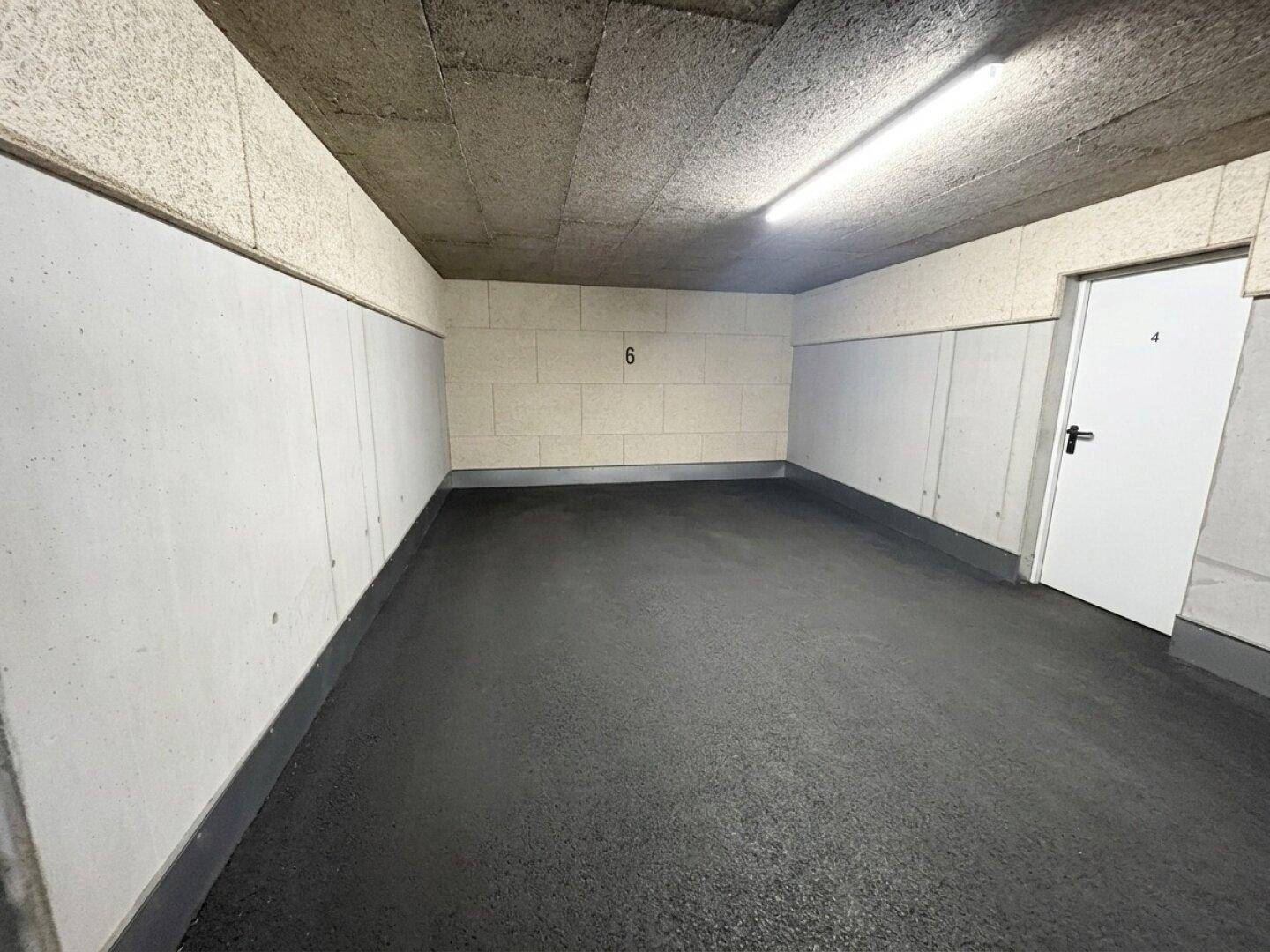 Leere und saubere Tiefgarage mit Betonwänden und glattem Boden.