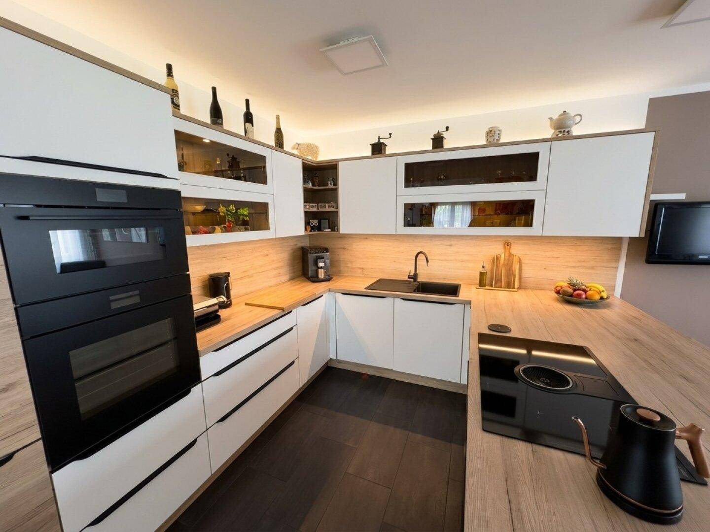 Detailansicht der modernen Küche mit Induktionskochfeld, Backofen und Holzarbeitsplatte.