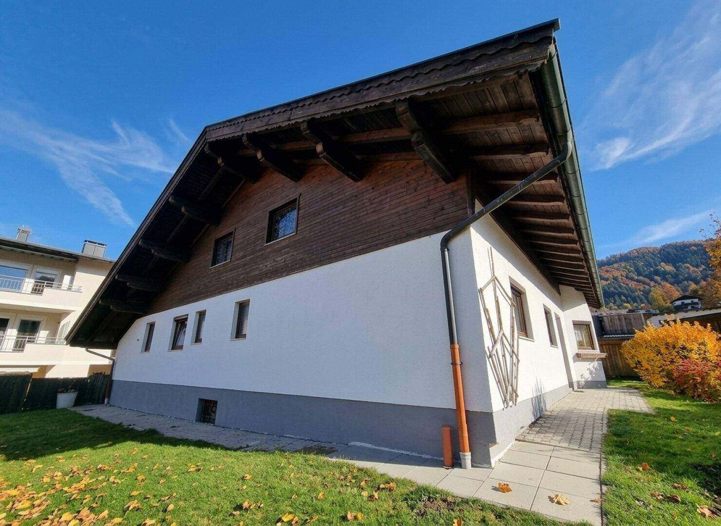 Seitenansicht des Hauses mit traditionellem Dachüberstand, Holzfassade und gepflegtem Gartenbereich.