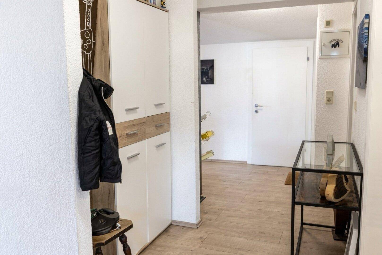 Eingangsbereich mit Laminatboden, weißem Schrank und Garderobe, hell und funktional gestaltet.