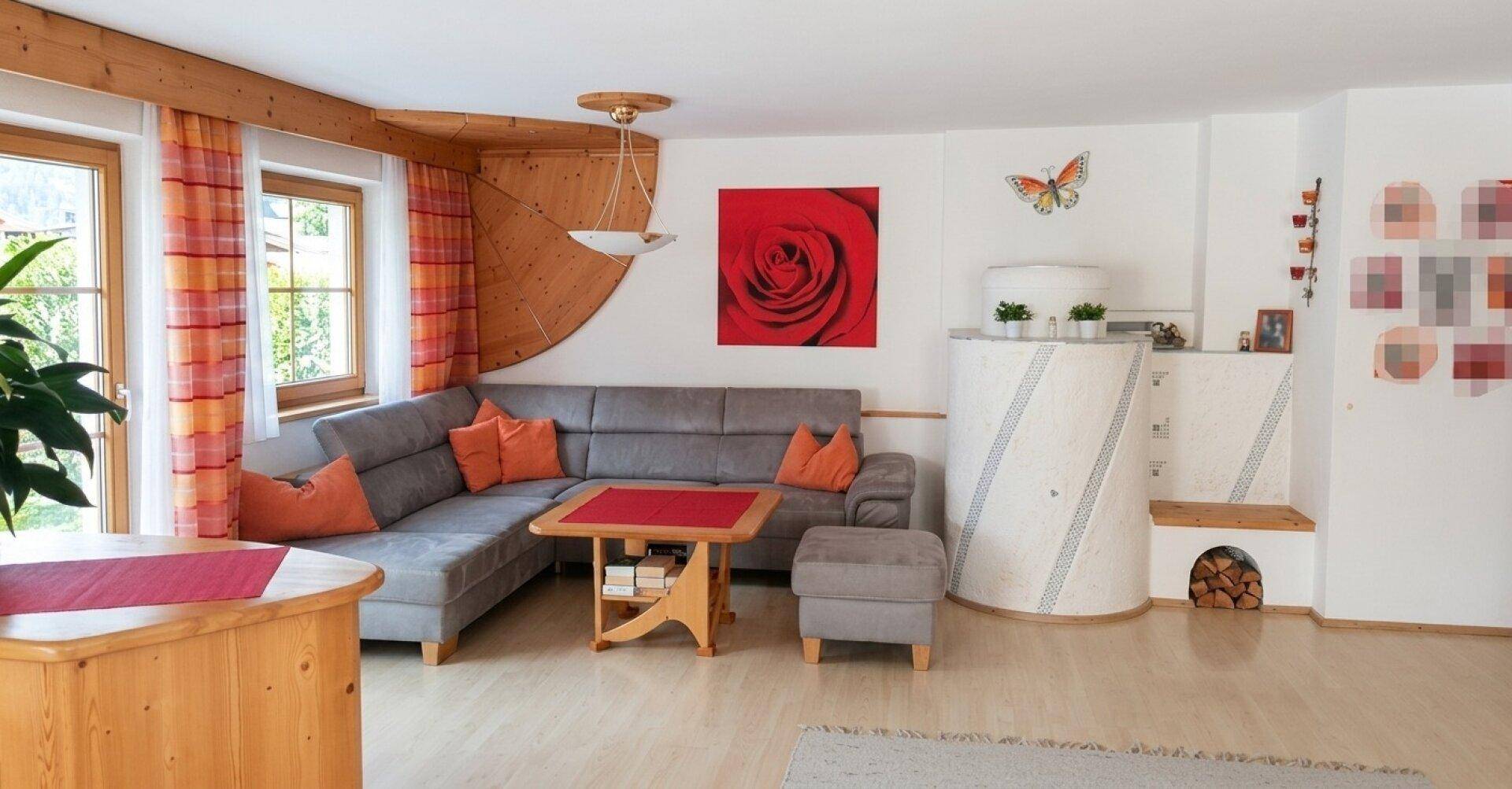 Gemütliches Wohnzimmer im alpinen Stil mit Kachelofen, Ecksofa und Holzelementen.