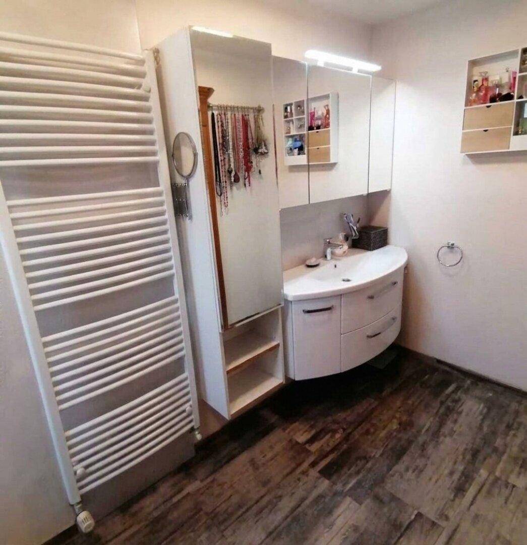 Modernes Badezimmer mit Waschtisch, Spiegelschrank und beheiztem Handtuchhalter.