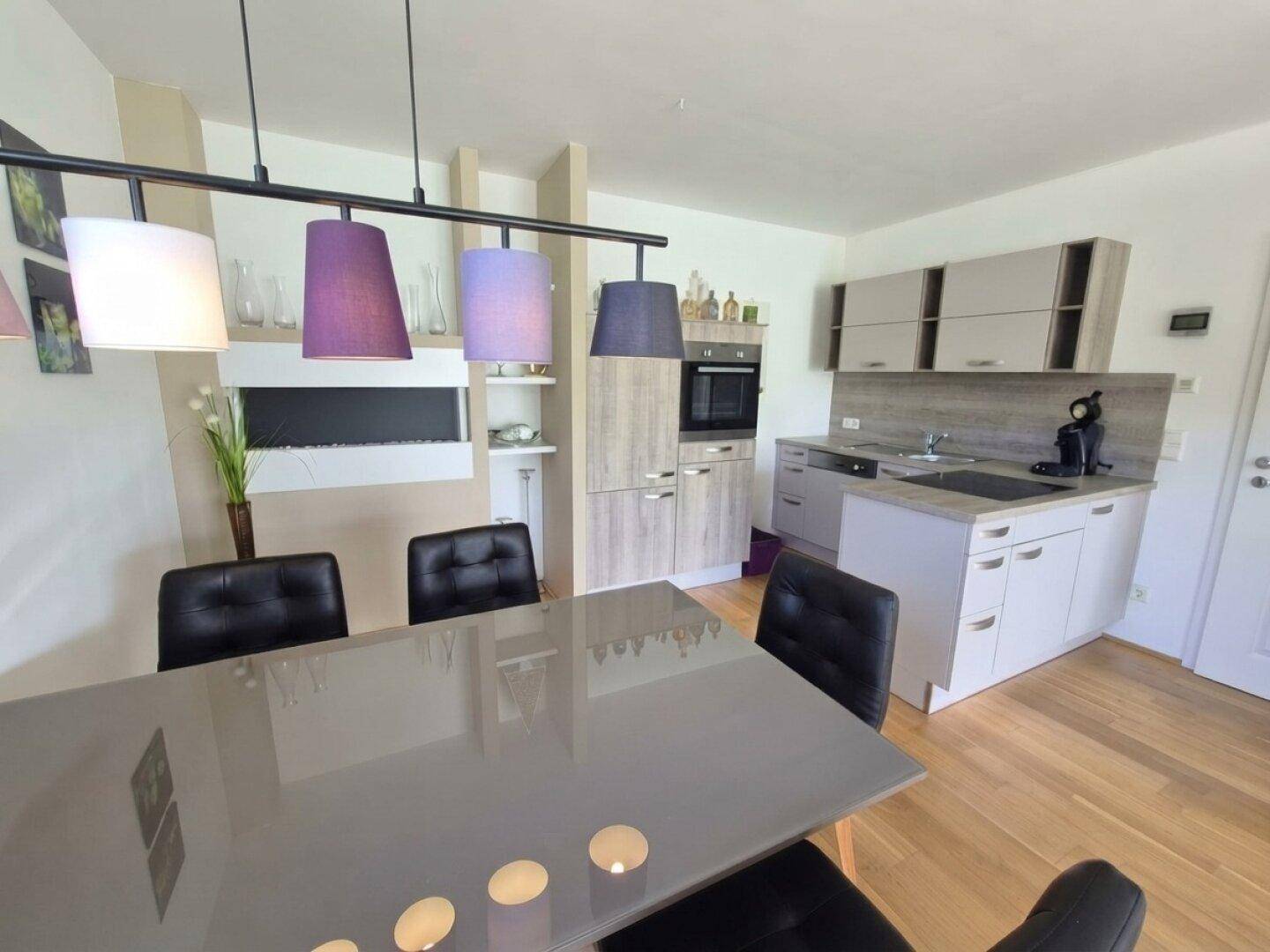 Moderne Küchenzeile mit Essbereich, Induktionskochfeld und stilvollen Hängelampen.