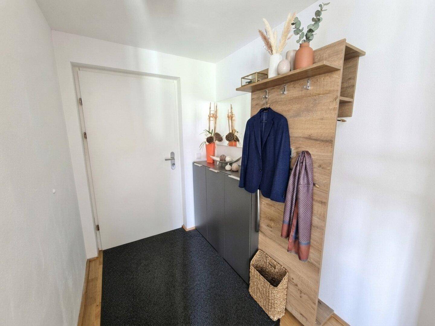 Heller Eingangsbereich mit Garderobe, Schuhschrank und Holzboden.