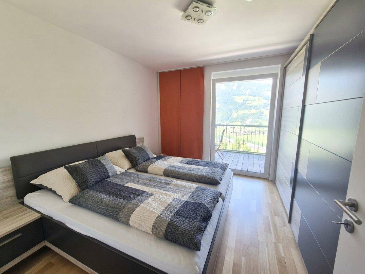 Gemütliches Schlafzimmer mit Doppelbett, Kleiderschrank und Balkonzugang mit Bergblick.