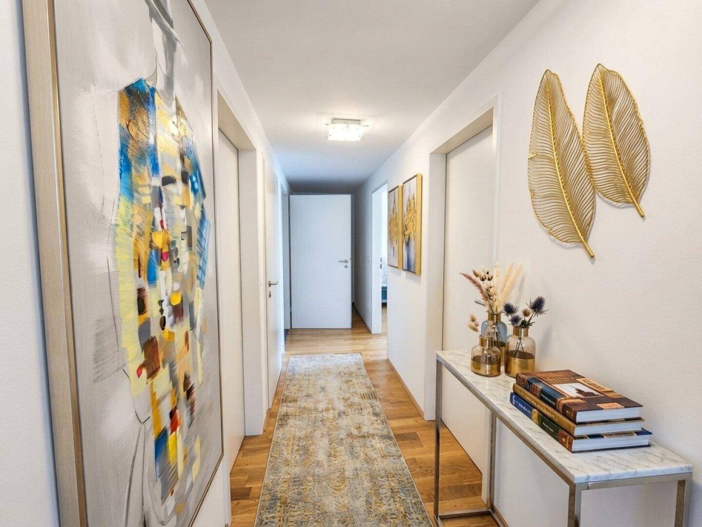 Langer Flur mit Holzboden, modernen Kunstwerken und einer Konsole.