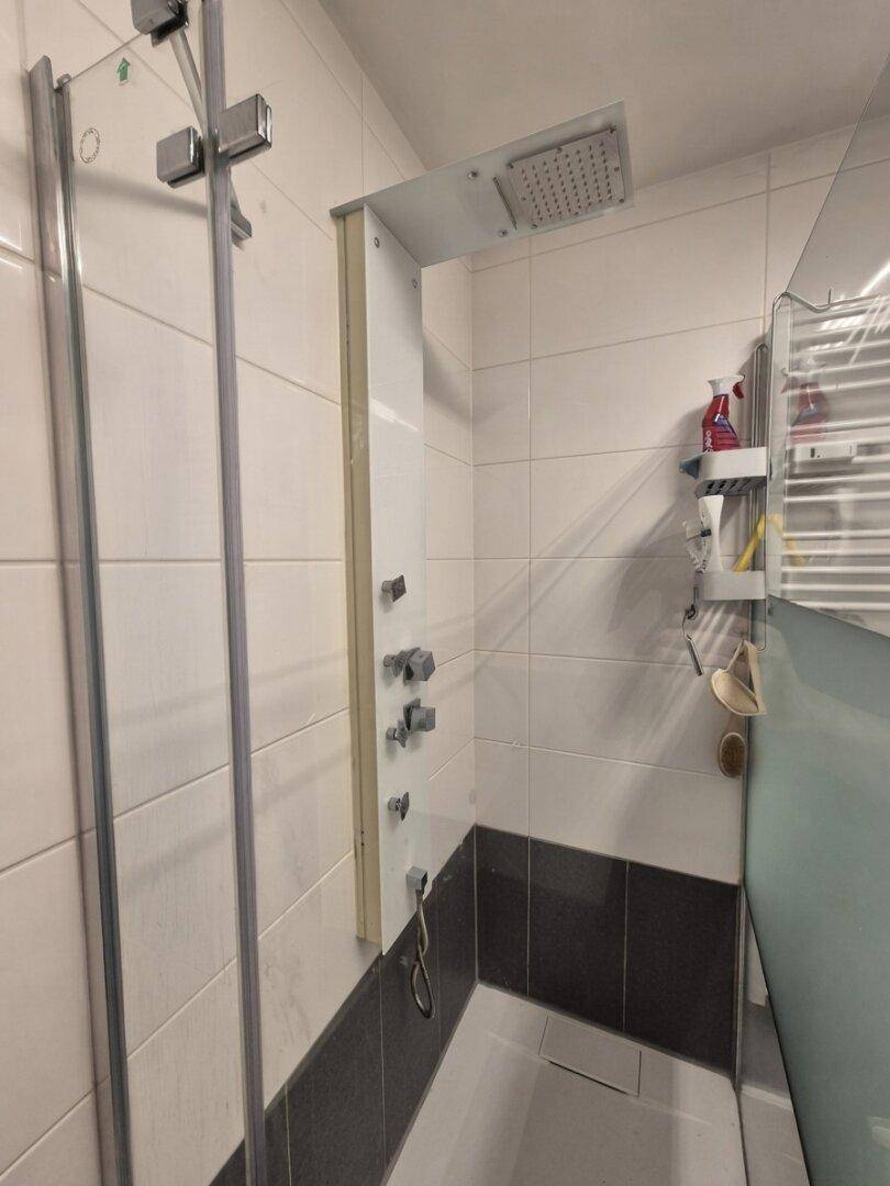 Geräumige Dusche mit Regenduschkopf und modernen Armaturen in einem gefliesten Badezimmer.