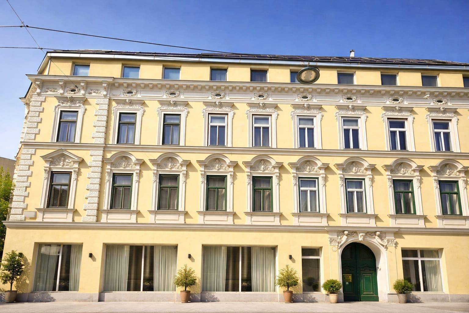 Historisches Gebäude mit gelber Fassade und reich verzierten Fenstern.