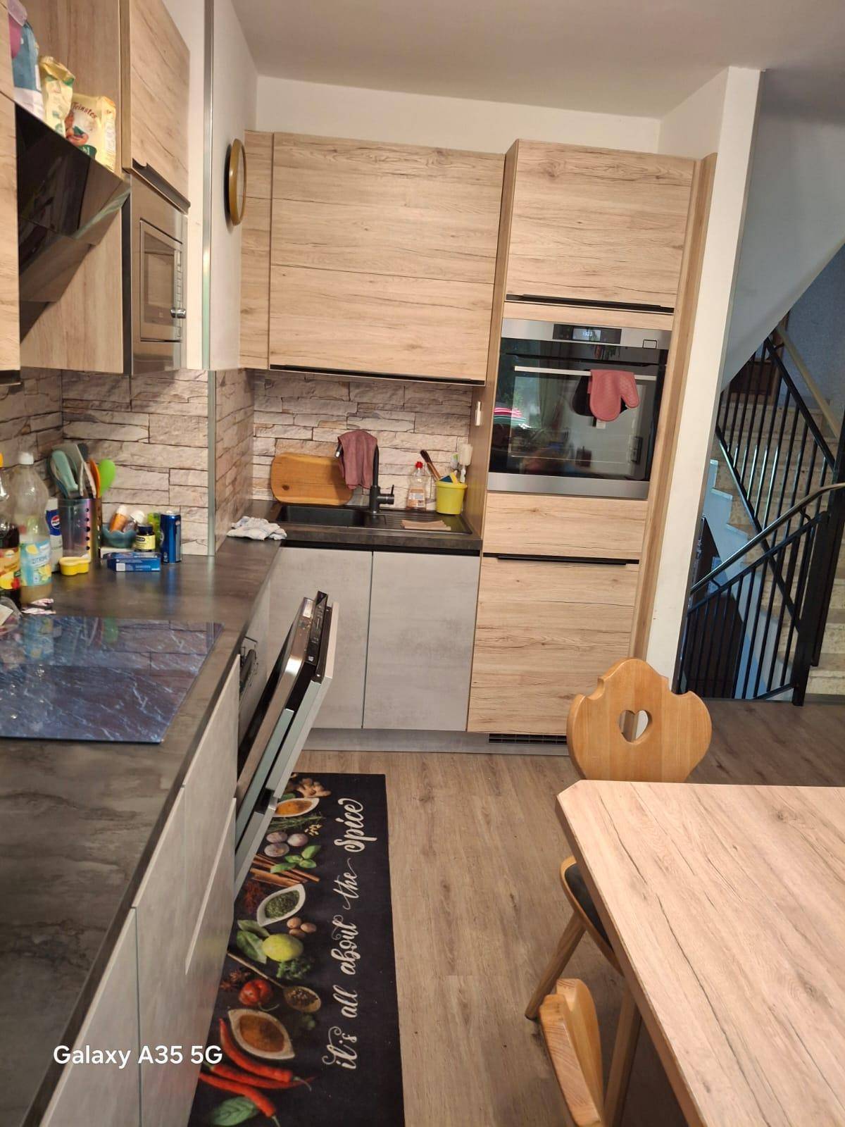 Moderne Küche mit hellen Holzfronten, integriertem Backofen und Essbereich mit Holztisch.