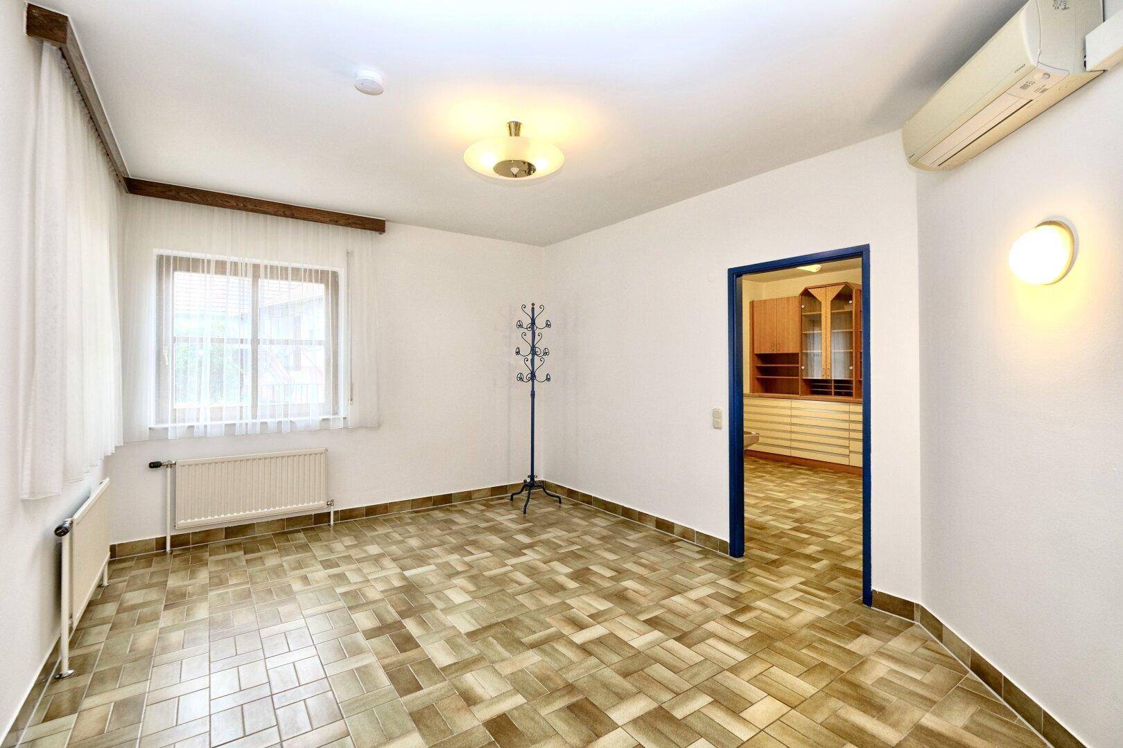 Heller Raum mit Klimaanlage, Fenster und einem gemusterten Fliesenboden, ideal als Büro.
