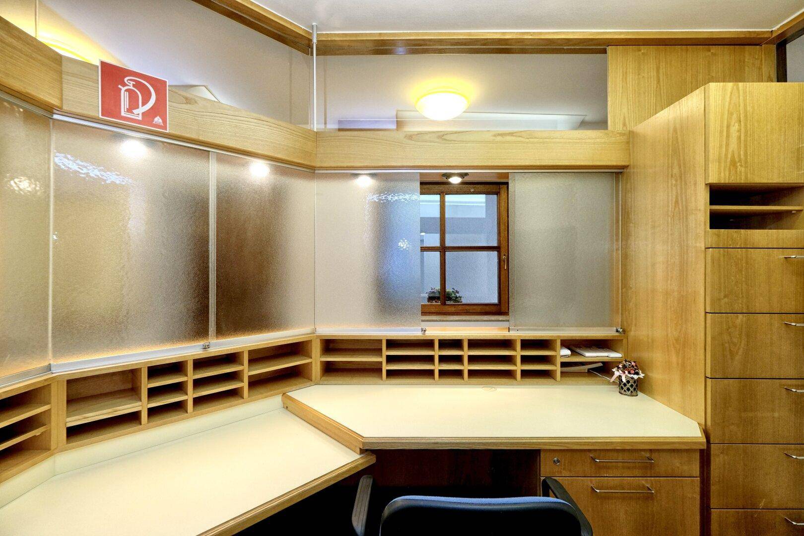 Funktionaler Bürobereich mit integriertem Schreibtisch, Regalen und Ablagefächern aus Holz.