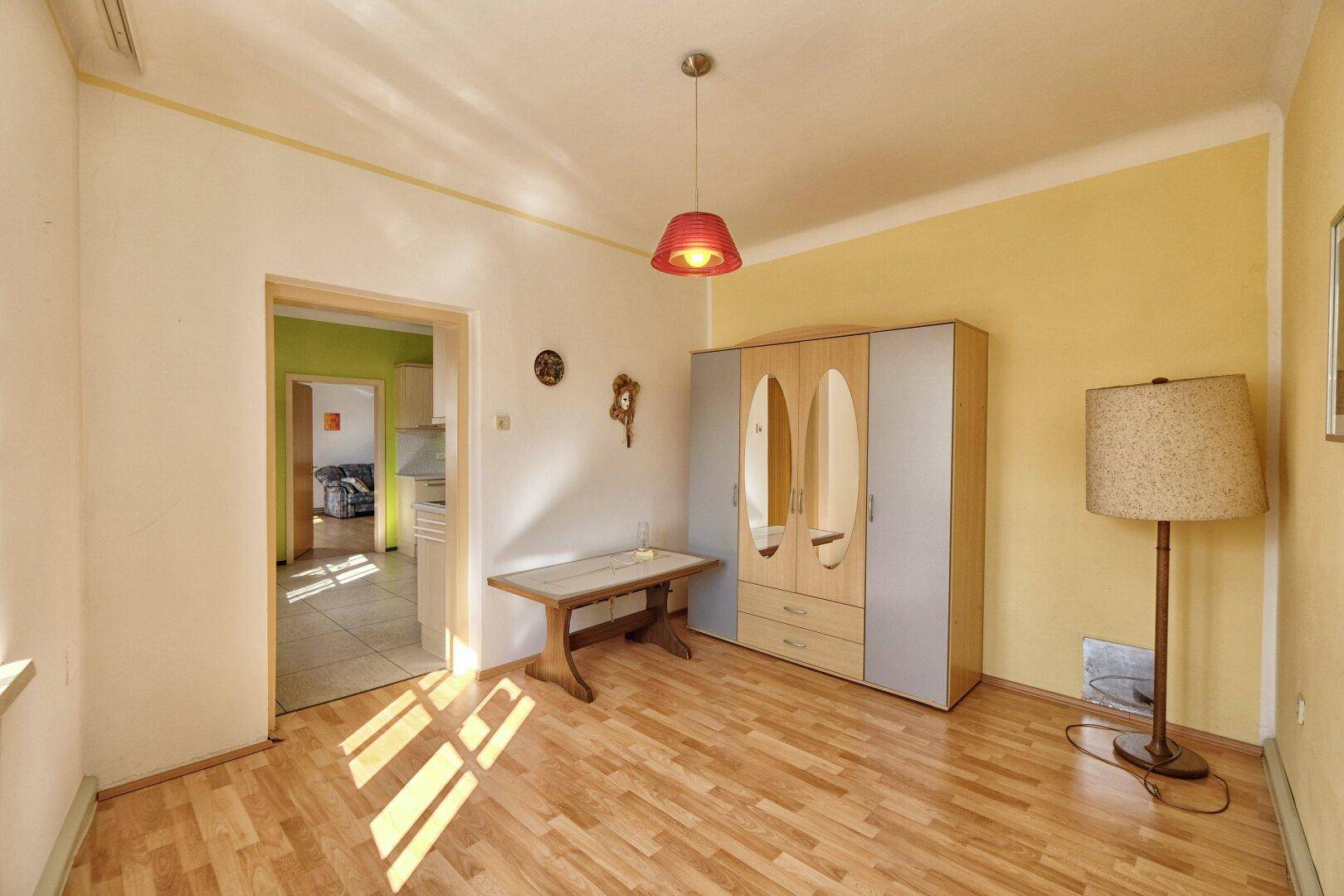 Heller Raum mit Holzboden, gelben Wänden und einem Schrank, der als Stauraum dient.