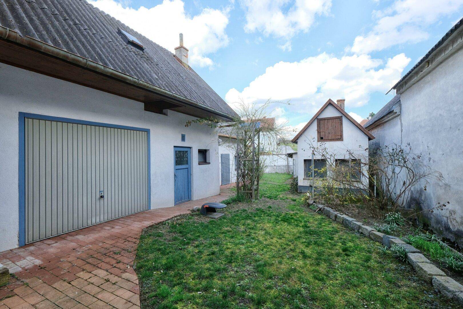Hinterhof mit Rasenfläche, einem kleinen Nebengebäude und Potenzial zur Gestaltung.