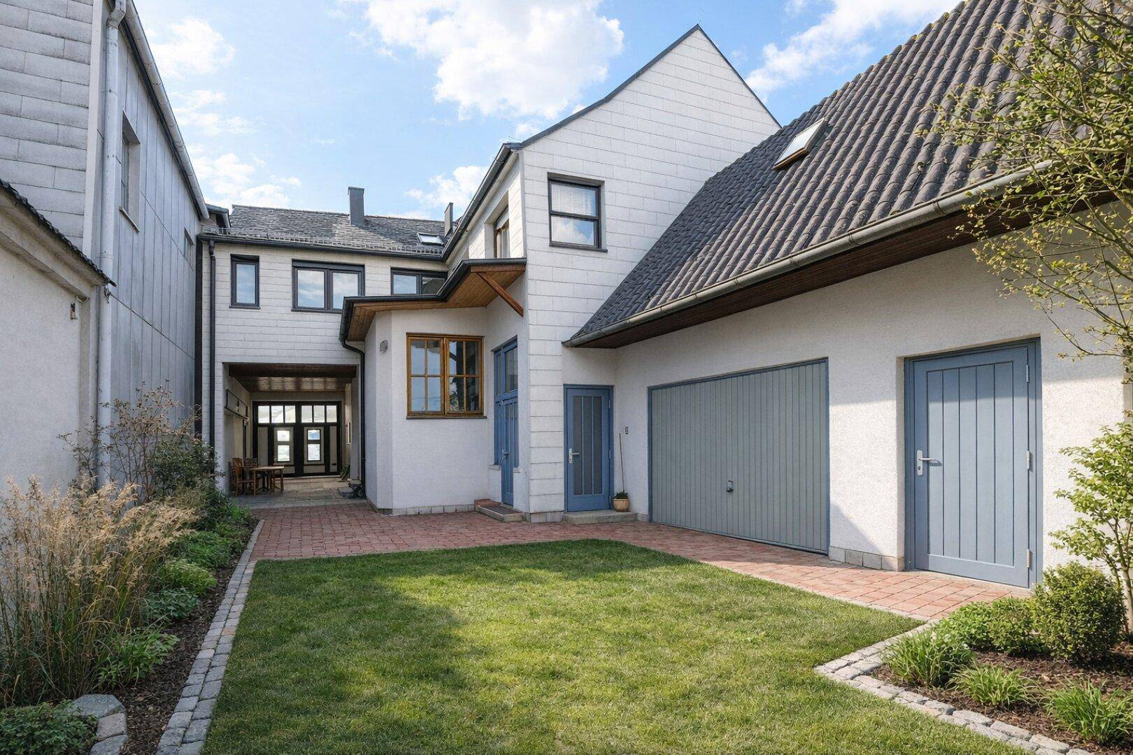 Ansicht des Hauses mit Garage, gepflegtem Vorgarten und Zugang zu einem überdachten Bereich.