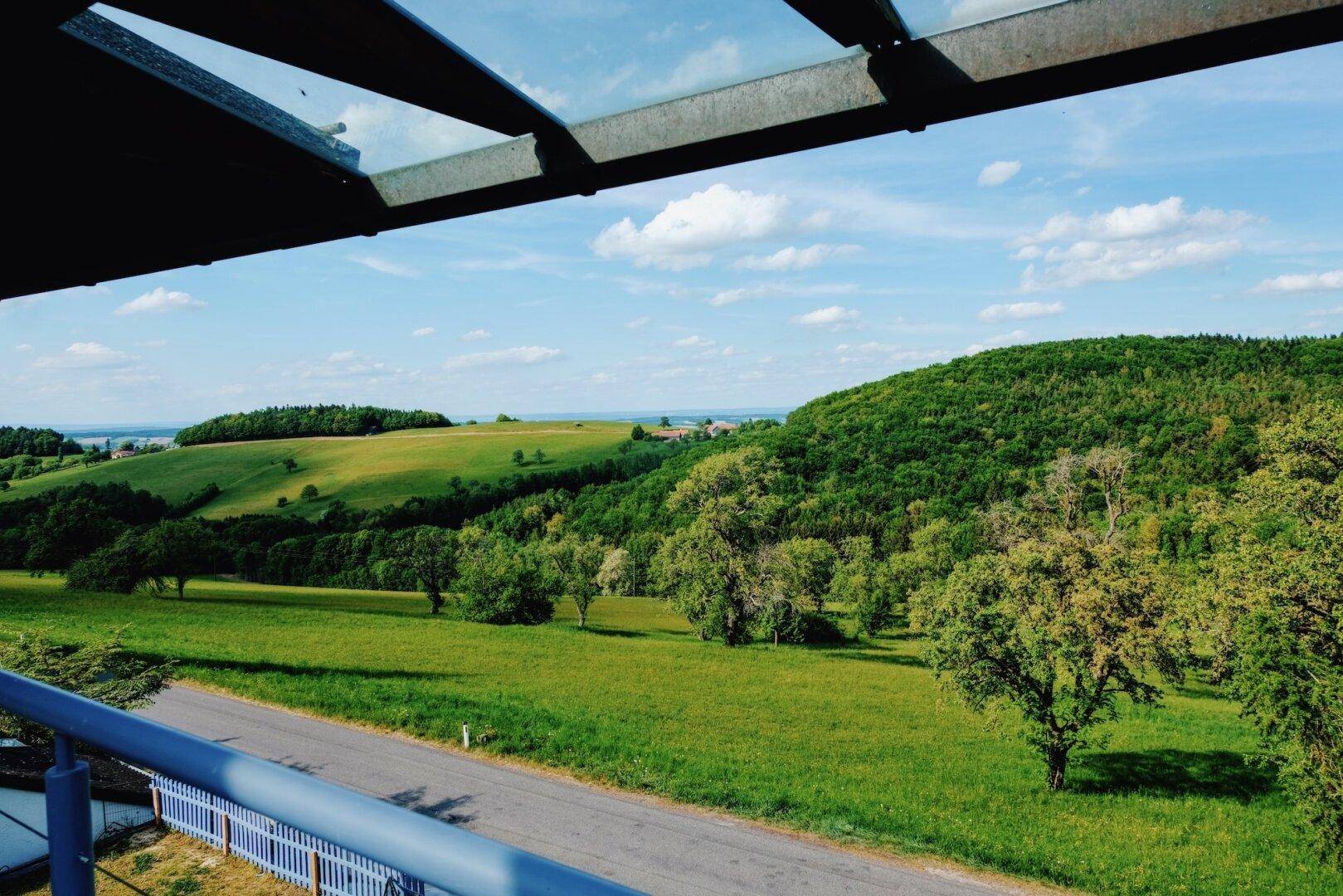 Malerischer Ausblick von der Terrasse auf sanfte Hügel und weite grüne Felder.