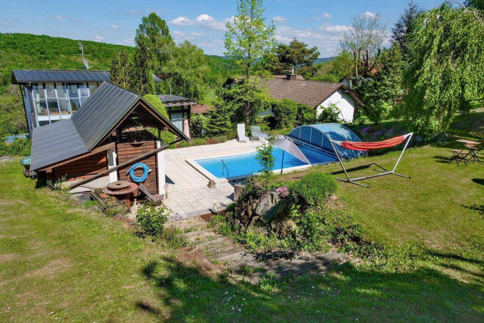 Weitläufiger Garten mit Pool, Hängematte und einem kleinen Holzhaus.