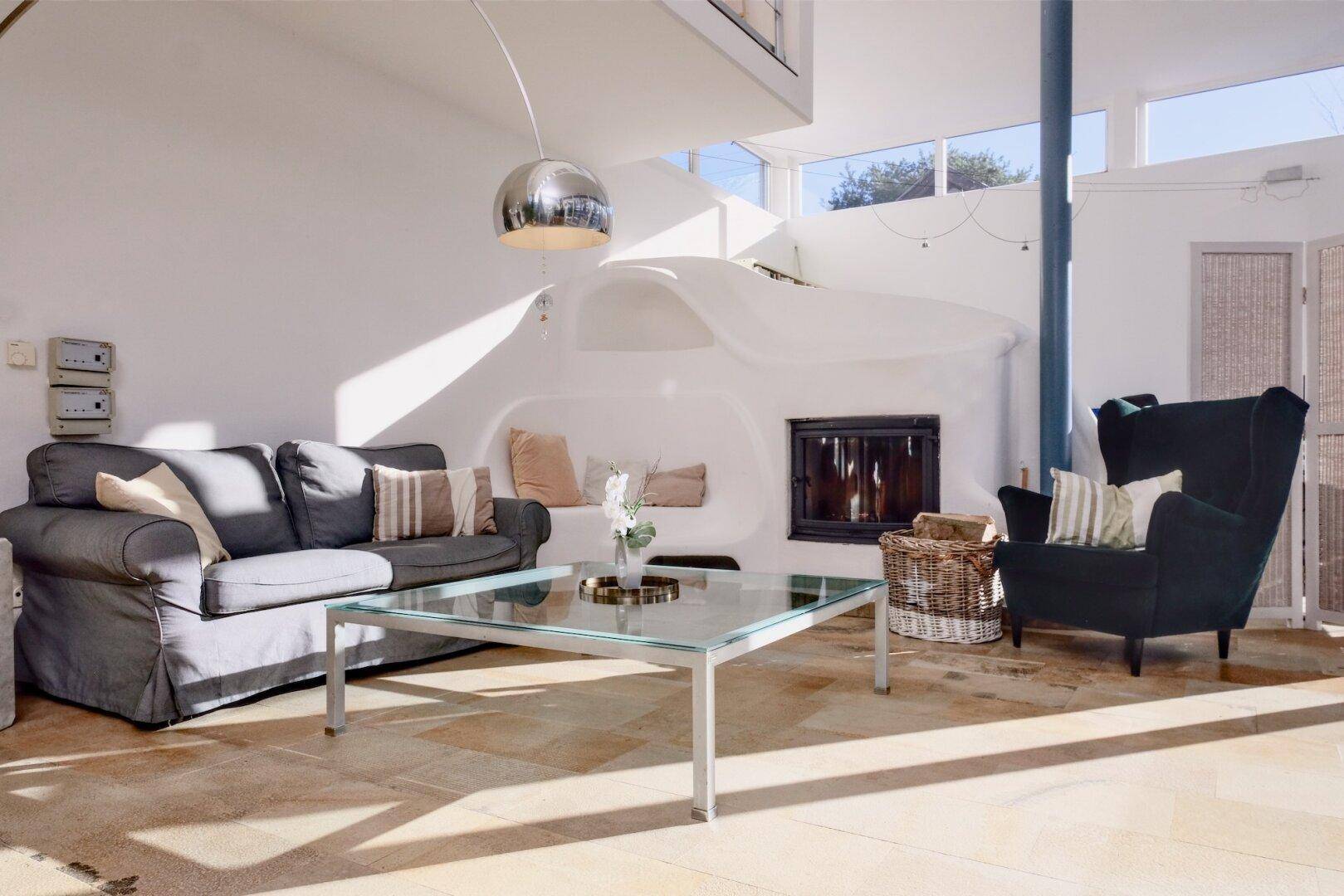 Gemütliches Wohnzimmer mit Kamin, bequemen Sofas und Steinfliesenboden.