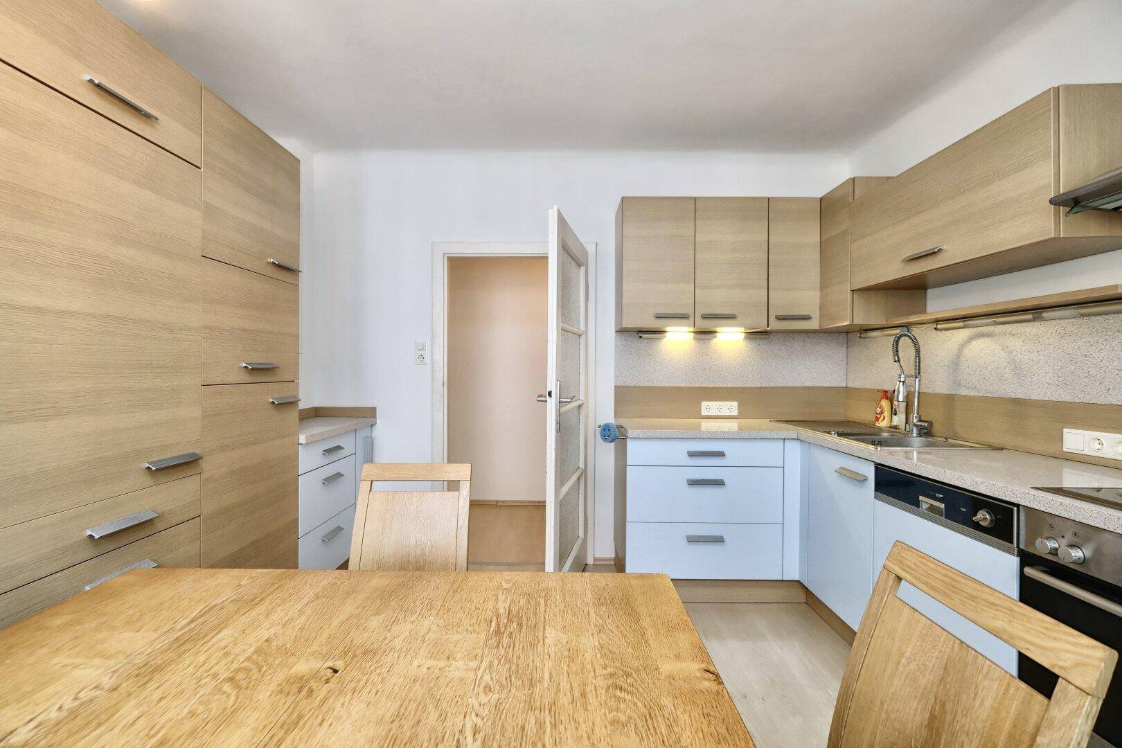 Helle Küche mit Holzelementen, integrierten Geräten und Essbereich.